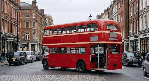 A classic Routemaster double-decker bus with its open rear platform, on a London street